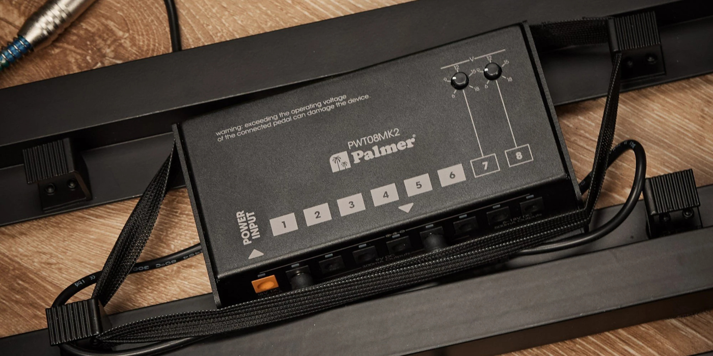 A Palmer pedal power supply mounted underneath a guitar pedalboard