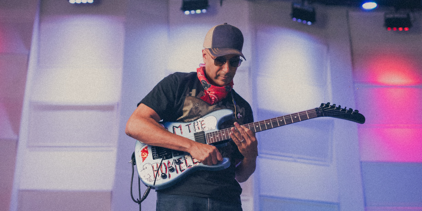 Tom Morello playing his signature Fender Arm The Homeless guitar on an illuminated stage