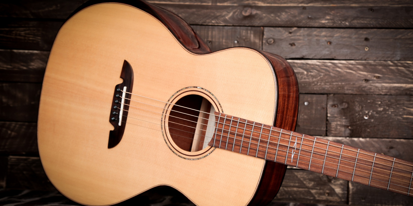 An angled Alvarez acoustic guitar body and neck against a wooden background