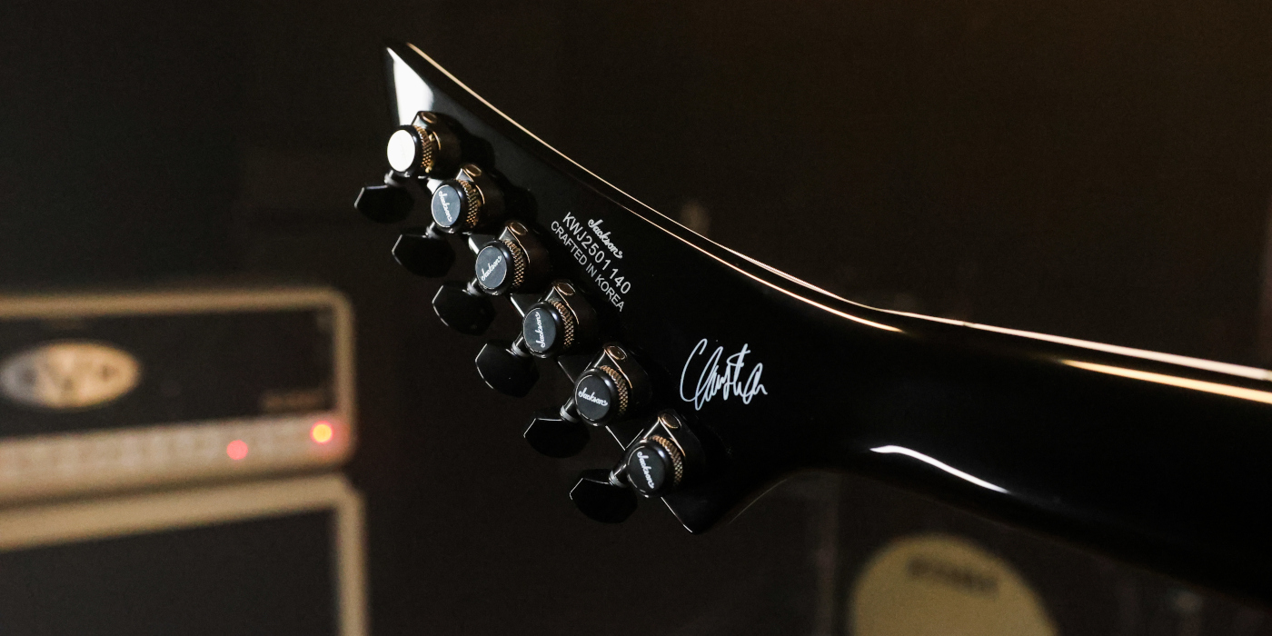 A photo of the back of a reversed Jackson guitar headstock fitted with locking guitar tuners