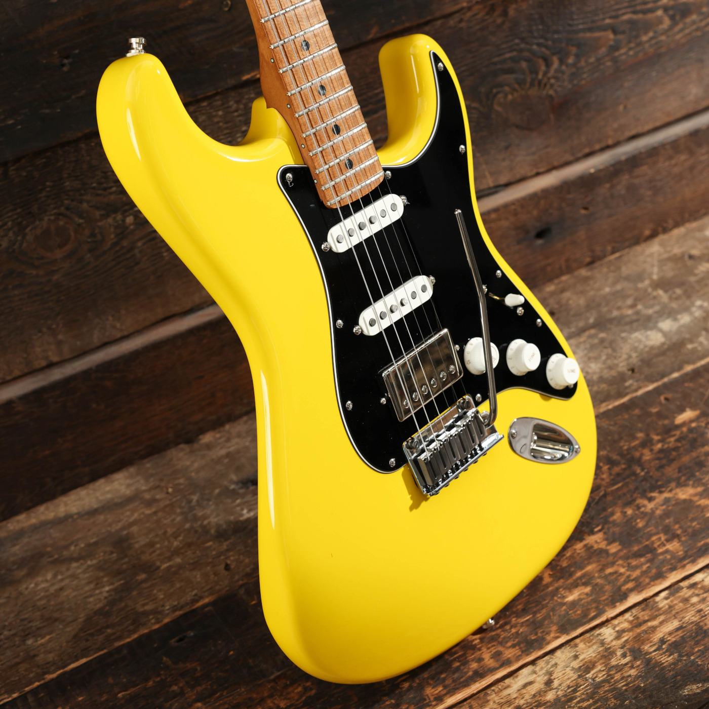A Fender American Ultra II Stratocaster HSS in Graffiti Yellow body at an angle against a wooden background