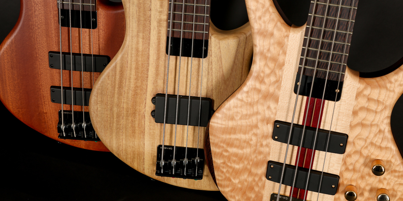 A photo of three natural finished Tobias basses lined up with Bartolini pickups
