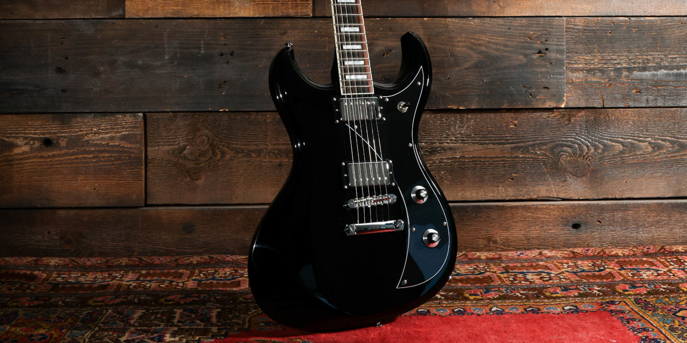 A Dunable Gnarwhal DE Series guitar in gloss black against a wooden background