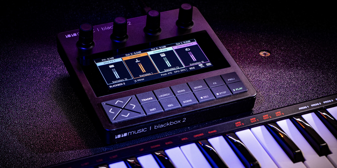 A dark, neon-lit lifestyle photo of the 1010music Blackbox 2 sampler placed behind a keyboard controller