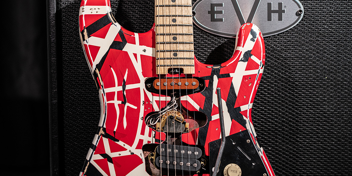 A cool lifestyle photo of the EVH Frankenstrat replica guitar leaning up against an EVH speaker cabinet