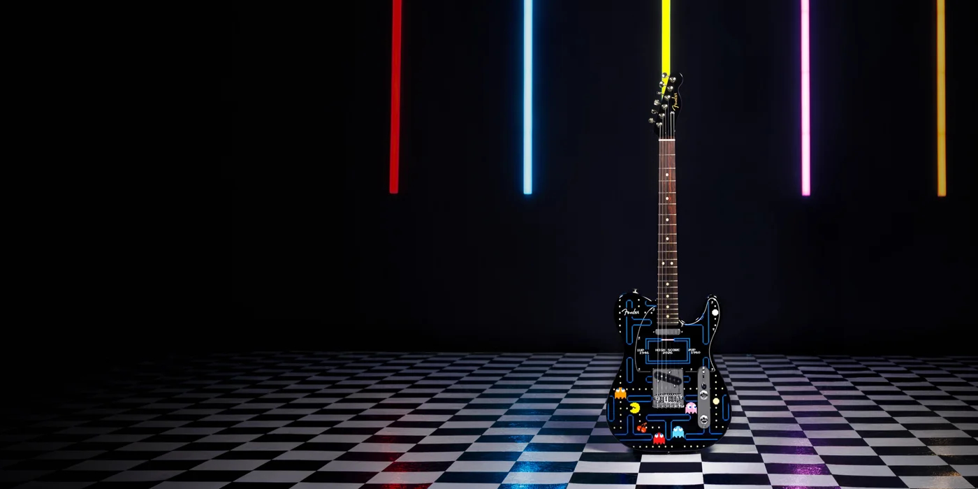 A photo of the limited edition Fender Pac-Man Player II Telecaster on a tiled floor with multicoloured light beams behind it