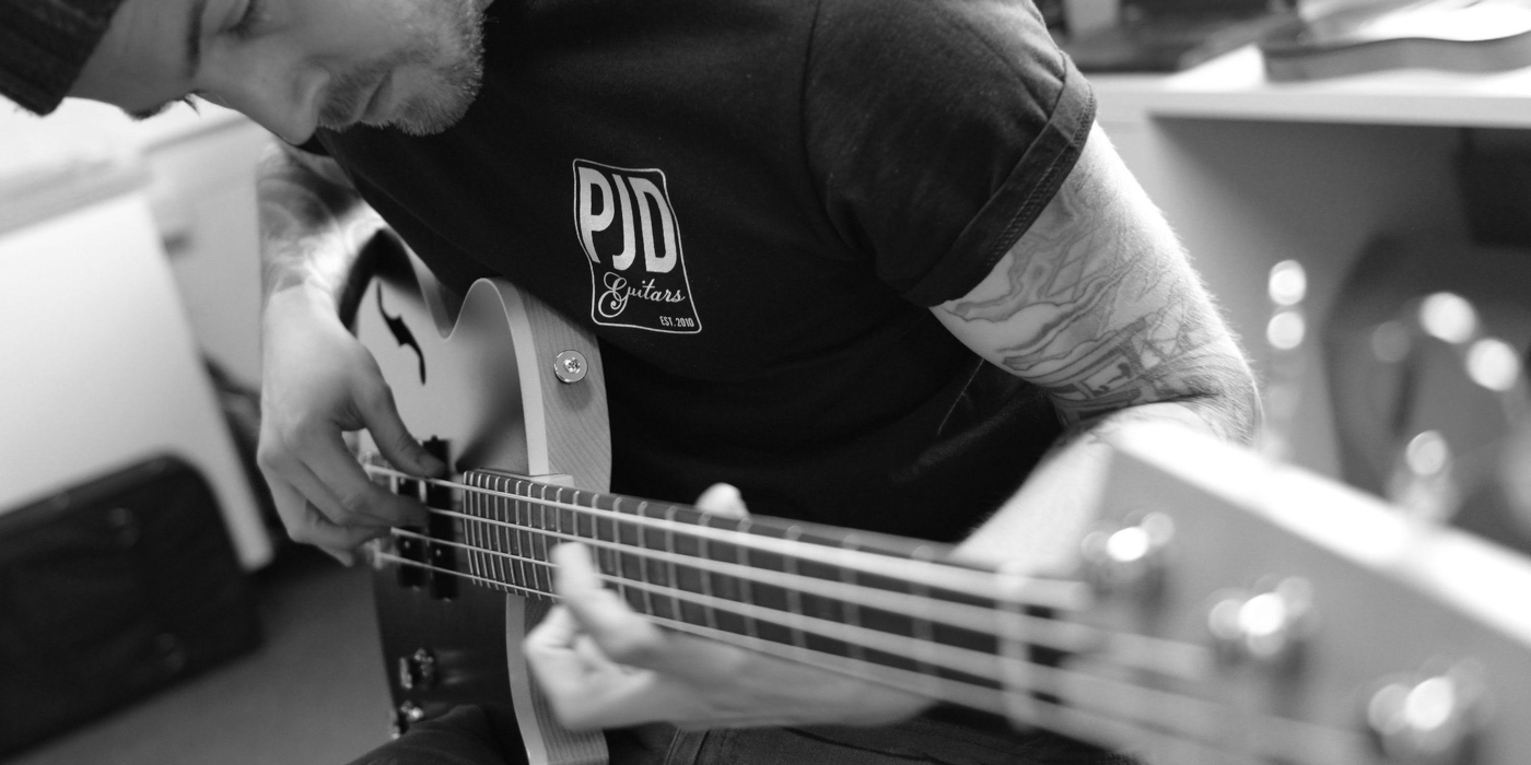 A photo of PJD Guitars founder Leigh Dovey playing a custom PJD bass guitar