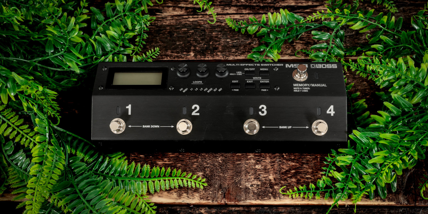 The Boss MS-3 multi-effects switcher on a wooden surface surrounded by leaves