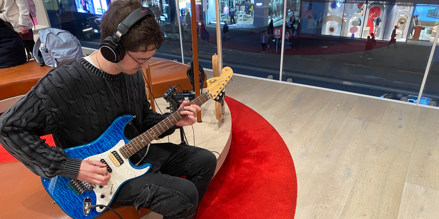 A man playing the Fender Michiya Haruhata signature Stratocaster in Caribbean Blue Trans in the Fender Flagship Tokyo shop