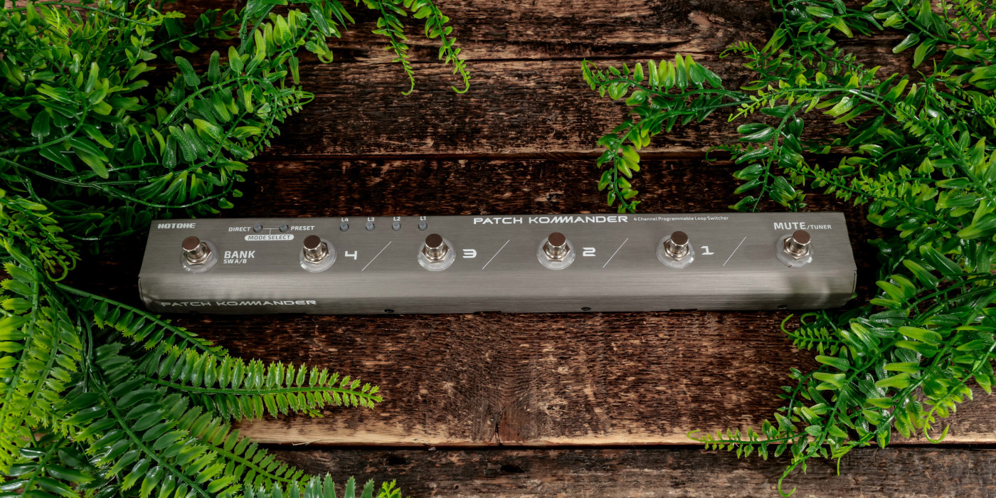The Hotone Patch Kommander pedal switching system on a wooden surface surrounded by leaves