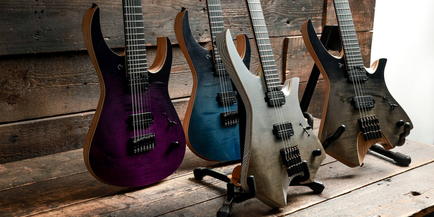 Four modern electric guitars lined up at an angle on a wooden surface
