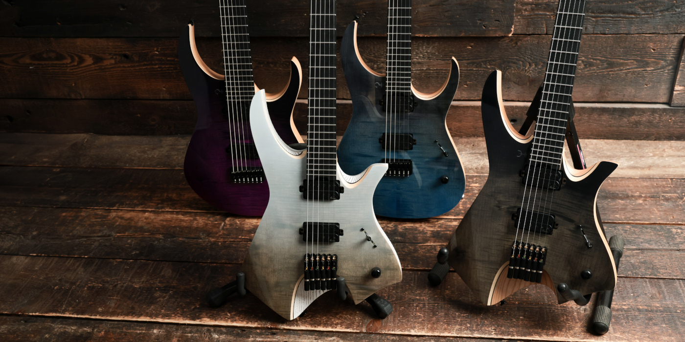 Various Infinia guitars lined up on stands against a wooden background