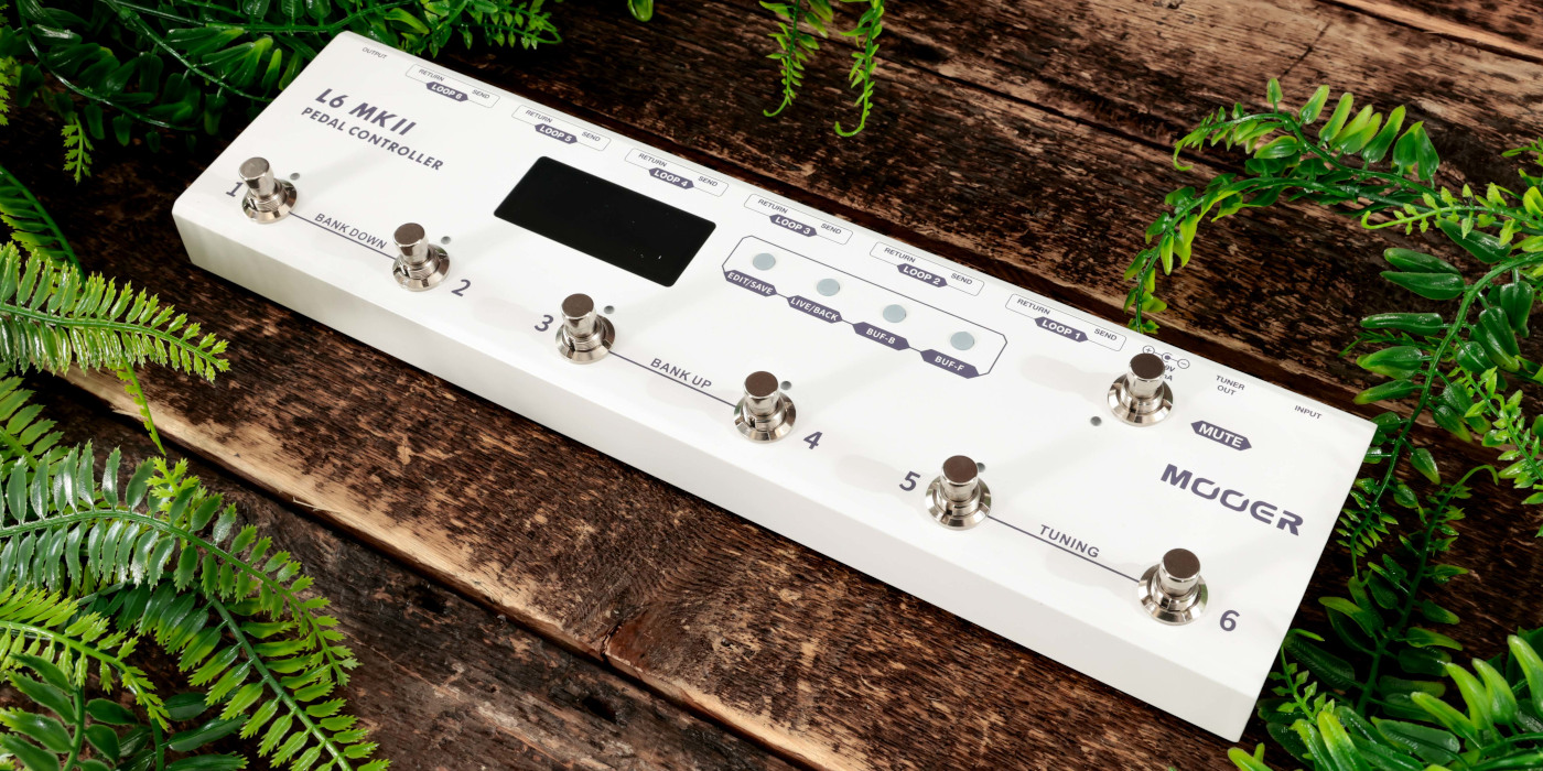 The Mooer L6 MKII pedalboard switcher on a wooden surface surrounded by foliage