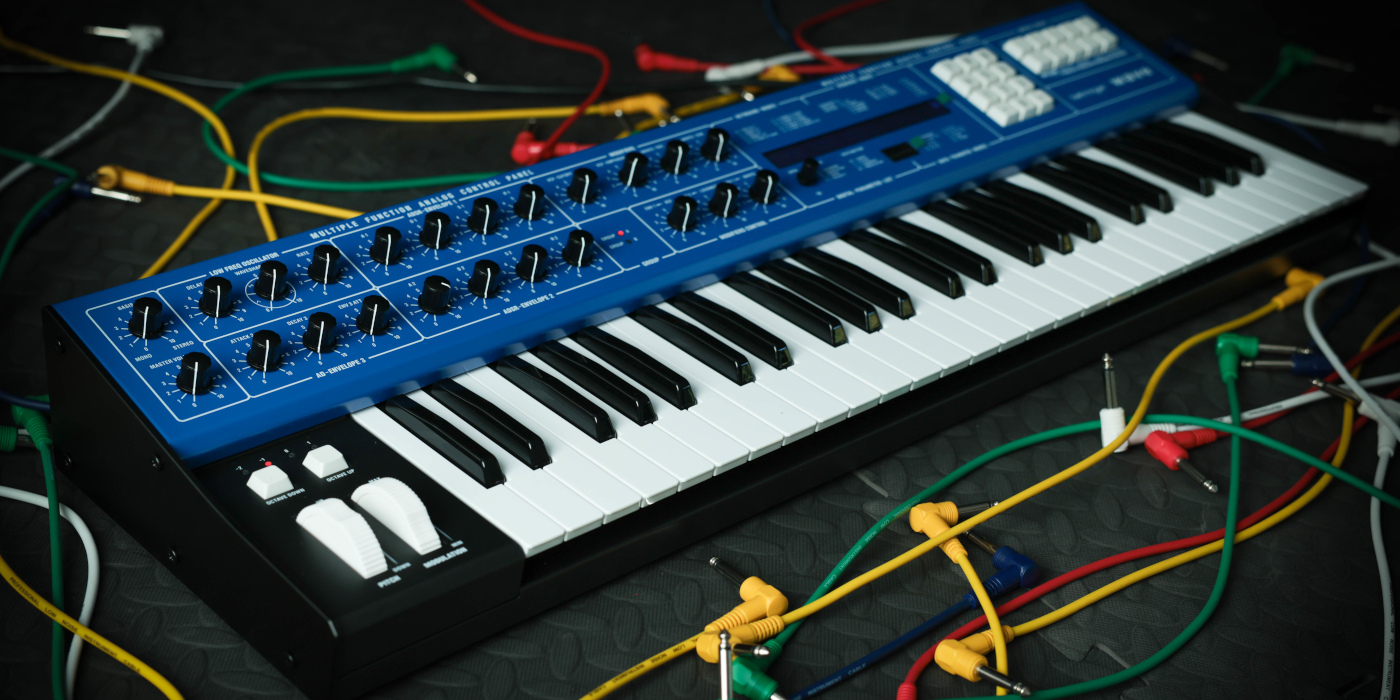 Behringer Wave synthesizer lifestyle photo angled surrounded by multi-coloured patch cables